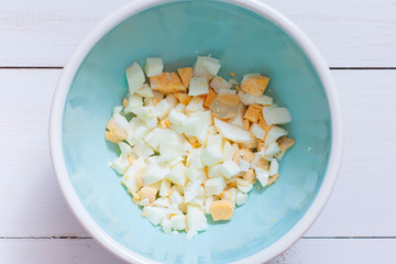Step-by-step preparation of salad with shrimps, fresh cucumber, eggs and cheese, step 2 - adding ingredients - boiled egg, top view, horizontal