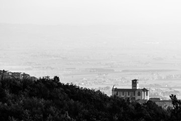 Beautiful view of Assisi town (Umbria) in autumn from an unusual place, behind an hill with trees
