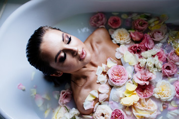 Obraz na płótnie Canvas Beautiful girl in the bathroom with many flowers.