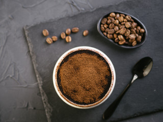 Top view of tiramisu in a glass cup on stone plate over black concrete background, Copy space.