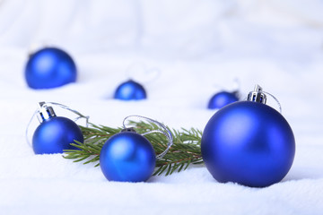 Merry Christmas background with blue balls, christmas tree on snow with snowflakes falling from a blue sky.