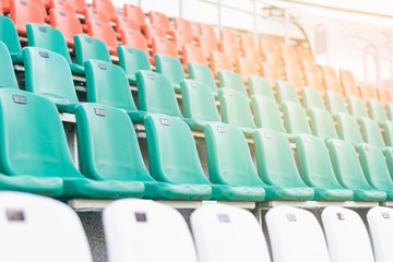 Fototapeta premium Plastikowe siedziska w kolorze białym, czerwonym i miętowym, ustawione w rzędach na stadionie. Pojęcie zdrowego stylu życia, nieostrość.