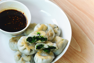 fried garlic chives dim sum or garlic steamed chives dumplings with spicy soy sauce in white plate on wood background