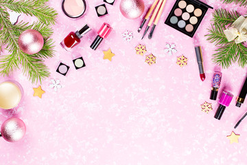 Make up cosmetics, presents and Christmas decorations on artistic pink background, copy space