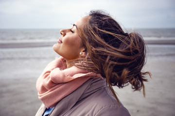 Pretty young female model with scarf on an wind going through her hair at the beach.