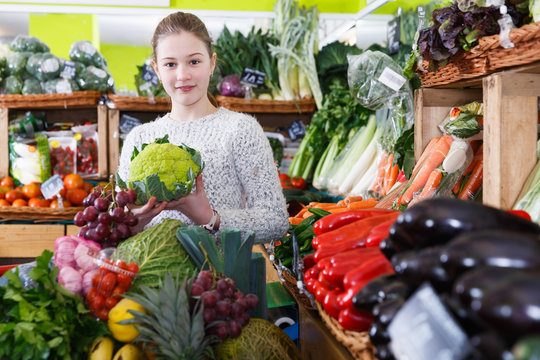 Cheerful girl in vegetable department of supermarket