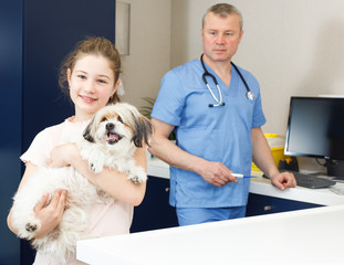 Smiling girl with puppy visiting veterinarian clinic
