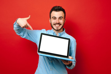 Happy young student pointing at his new laptop