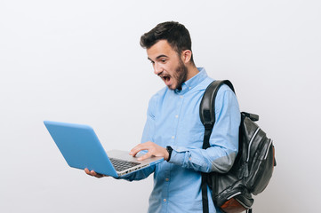 Young amazed man looking at laptop over white background
