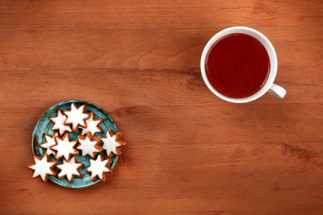 Christmas Zimtsterne, cinnamon star cookies, shot from the top on a rustic wooden background with hot chocolate and copy space