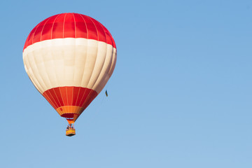 Red balloon against a blue sky. Aerostat. People in the basket. Fun. Summer entertainment. Romantic adventures.