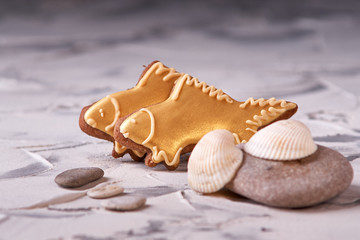 Sweet goldfish cookies and shells on gray background