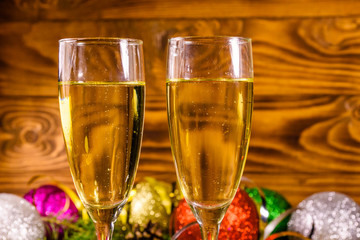 Two wineglasses with champagne and different christmas decorations on wooden table
