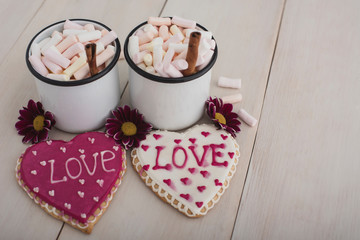 Romantic breakfast for valentine day. A delicious drink of marshmallows and heart-shaped cookies. Breakfast for lovers on a white  wooden table