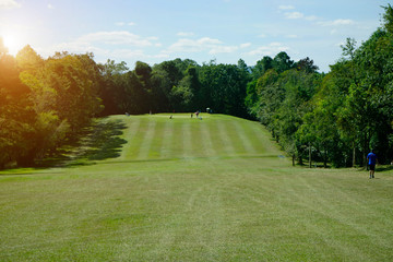 The evening golf course has sunlight shining down at golf course in Thailand