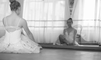 Young ballet dancer on a warm-up. The ballerina is preparing to perform in the studio. A girl in ballet clothes and shoes kneads by the handrails.