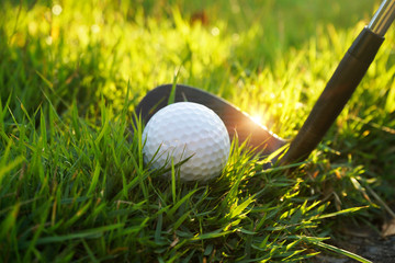 Golf ball and golf club in beautiful golf course with sunset background. Golf ball on green in golf...