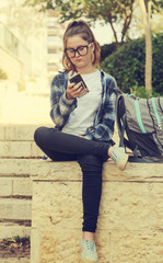 Portrait of tenage girl sitting outdoor with mobile phone