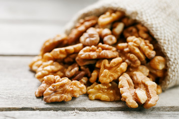 Walnuts in a burlap bag on a wooden gray background.