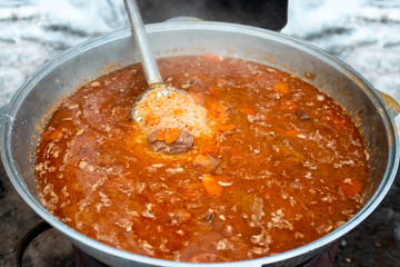 Cooking delicious pilaf in big cauldron outdoors. National Uzbek cuisine, a dish of rice, meat, vegetables and spices. Street food