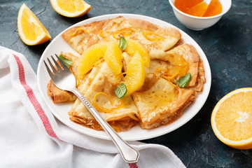 Crepes suzette - pancakes with orange sauce on dark blue background.