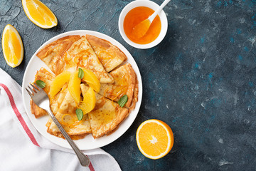 Crepes suzette - pancakes with orange sauce on dark blue background.