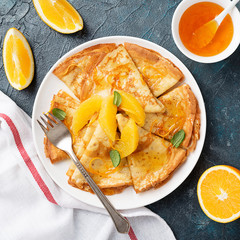 Crepes suzette - pancakes with orange sauce on dark blue background.