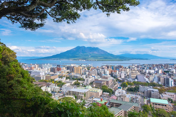 Cityscape with Sakurajima mountain, sea and blue sky background view from Shiroyama Park Observation park, Kagoshima, Kyushu, Japan