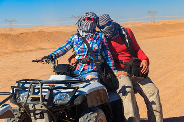 Obraz premium Young couple in safari trip through egyptian desert driving ATV. Quad bikes safari in the desert near Hurghada, Egypt