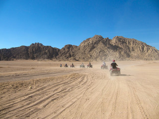 Fototapeta na wymiar Caravan ATV racing at high speed through the desert raising dust