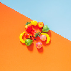 Tiny plastic fruit on an orange and light blue background. The concept of healthy eating.