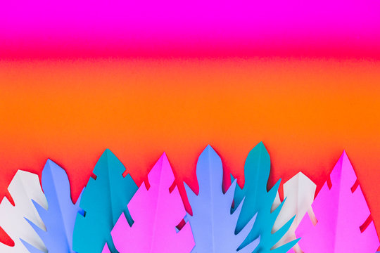 Multicolored paper tropical leaves on a gradient background with a blank space for text.