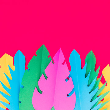 Multicolored paper tropical leaves on a bright pink background with a blank space for text. Minimal, Flat lay