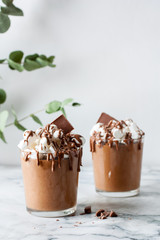 Chocolate mousse with marshmallows in a glass on a marble table