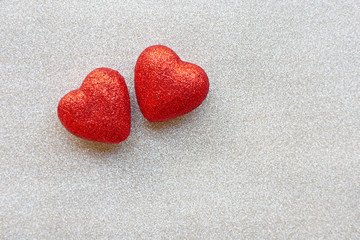 Fototapeta premium The red heart shapes on silver glitter paper background in love concept for valentines day