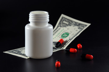 Pills and a jar of pills on a black background. Expensive and cheap medicines