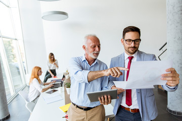 Mature boss and young business man working together in office