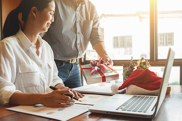 Group of young business people are celebrating in workplace with Santa hats in last working day. Young creative people are celebrating holiday in modern office. Merry Christmas and Happy New Year.