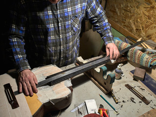 Installation frets on the neck of the guitar. The specialist checks the distance between the frets...