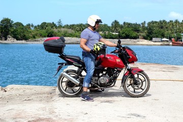 Biker on the background of the sea with a helmet in hand