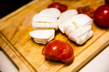 Mozzarella cheese and tomatoes on a wooden cutting board