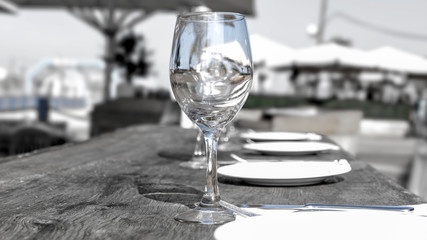 Empty wine glass on a wooden table in a cafe on a city beach. Israel