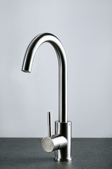 Modern water tap on grey background.