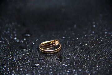 two wedding rings on a black background with water