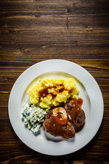 Grilled steak boiled potatoes and vegetable salad on wooden background