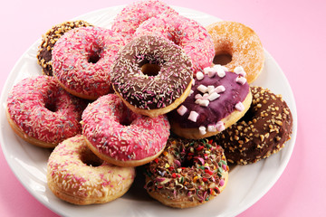 assorted donuts with chocolate frosted, pink glazed and sprinkles donuts