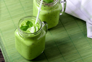 Green smoothie on green background made by avocado, lemon and kiwi.
