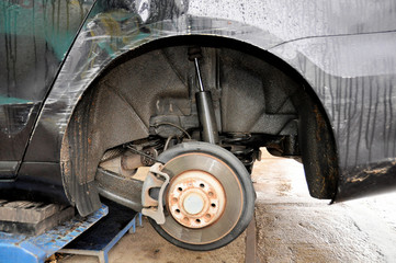 A close up view  brake disks and pads and wheel arch of  all wheel drive car when the tires have been taken off to be replaced