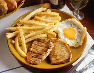 Plato combinado con dos trozos de lomo a la parrilla, un huevo frito y patatas fritas