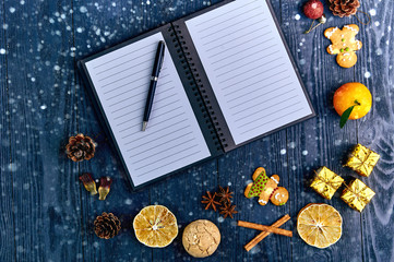 Notepad and pen in the circle of beautiful Christmas decorations. Fruits, sweets, cones and gifts for Christmas. All need to write a letter to Santa, a list of gifts, a list of things for next year.